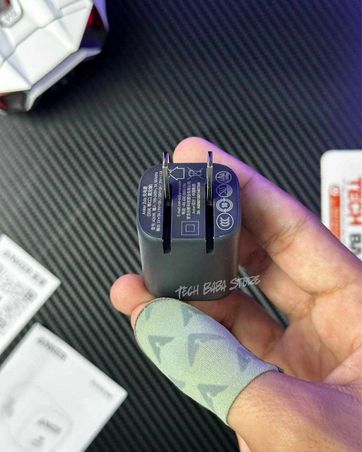 a hand holding a AnkerZolo30WCompactUSB-CGaNCharger and showing a pins also showing the techncal specifications. picture by techbabastore.pk