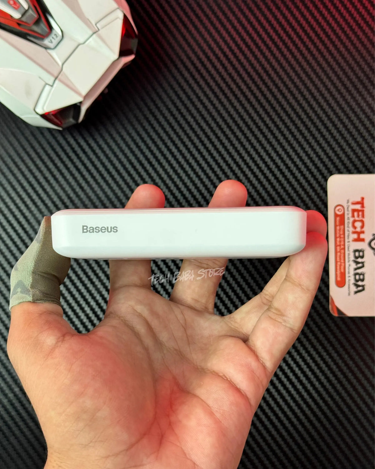 a hand holding a Baseus PPCXM10 Wireless PowerBank and showing a side view and also showing Baseus label on it .picture by TEchBabaStore.pk