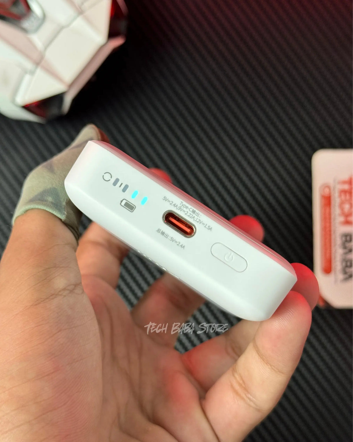 a hand holding Baseus PPCXM10 Wireless PowerBank and showing its real side which has a type c port with power button. picture by TechBabaStore.pk
