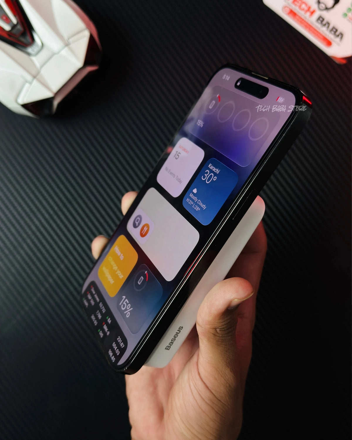 a hand holding iphone which is wirelessly charging with Baseus PPCXM10 Wireless PowerBank nd also showing side closeup view of atteched power bank with iphone. picture by TechBabaStore.pk