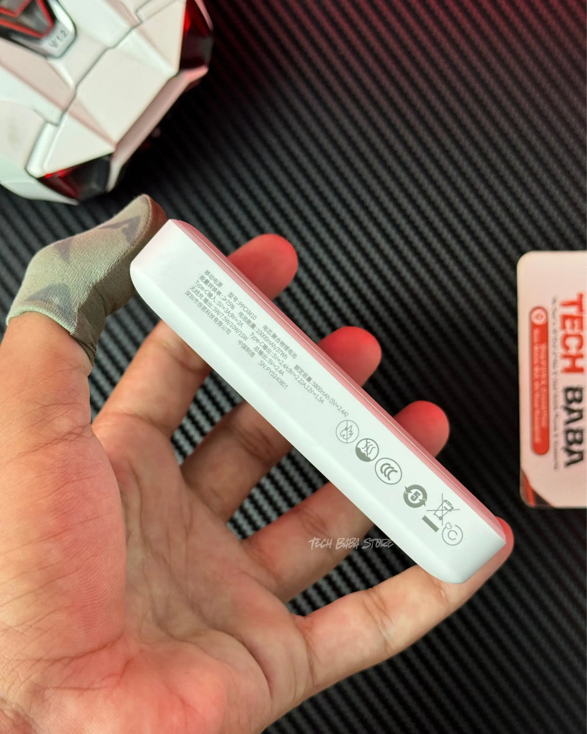A hand holding Baseus PPCXM10 Wireless PowerBank and showing side with technical specification. picture by TechBabaStore.pk