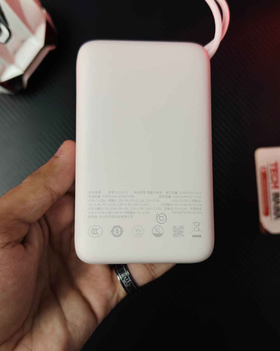 A hand holidng a pink colour Baseus Enerfill FC11 20000mAh 22.5W Power Bank showing a backside closeup view of its Technical Specifications - Picture by TechBabaStore.pk