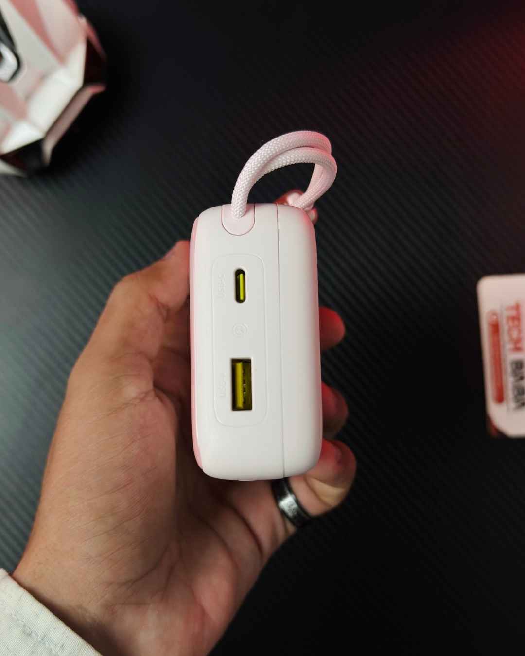 A hand holding a Pink Colour Baseus Enerfill FC11 20000mAh 22.5W Power Bank Ports specifications closeup view, showing a Type-C Port and a USB Type-A Port. Picture by TechBabaStore.pk