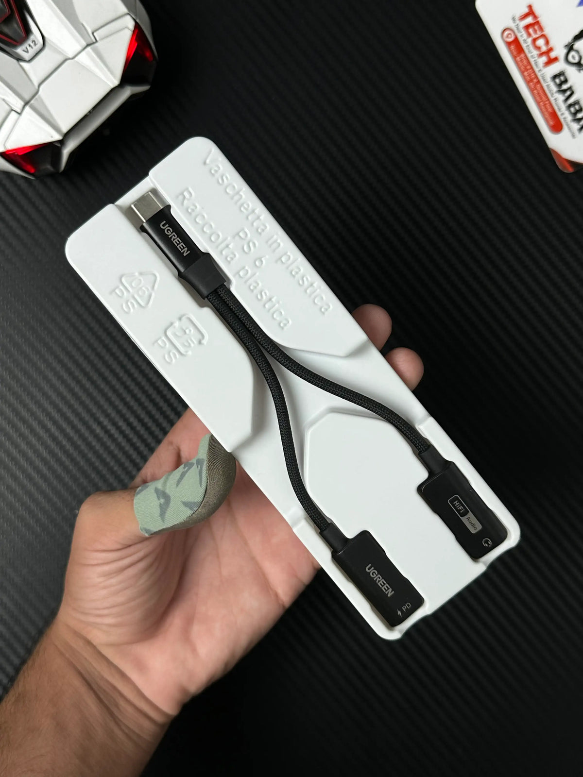 A hand holding UGREEN 25837 USB-C to 3.5mm Audio Adapter Pakistan which has showing Ctype and connector.picture by Techbabastore.pk