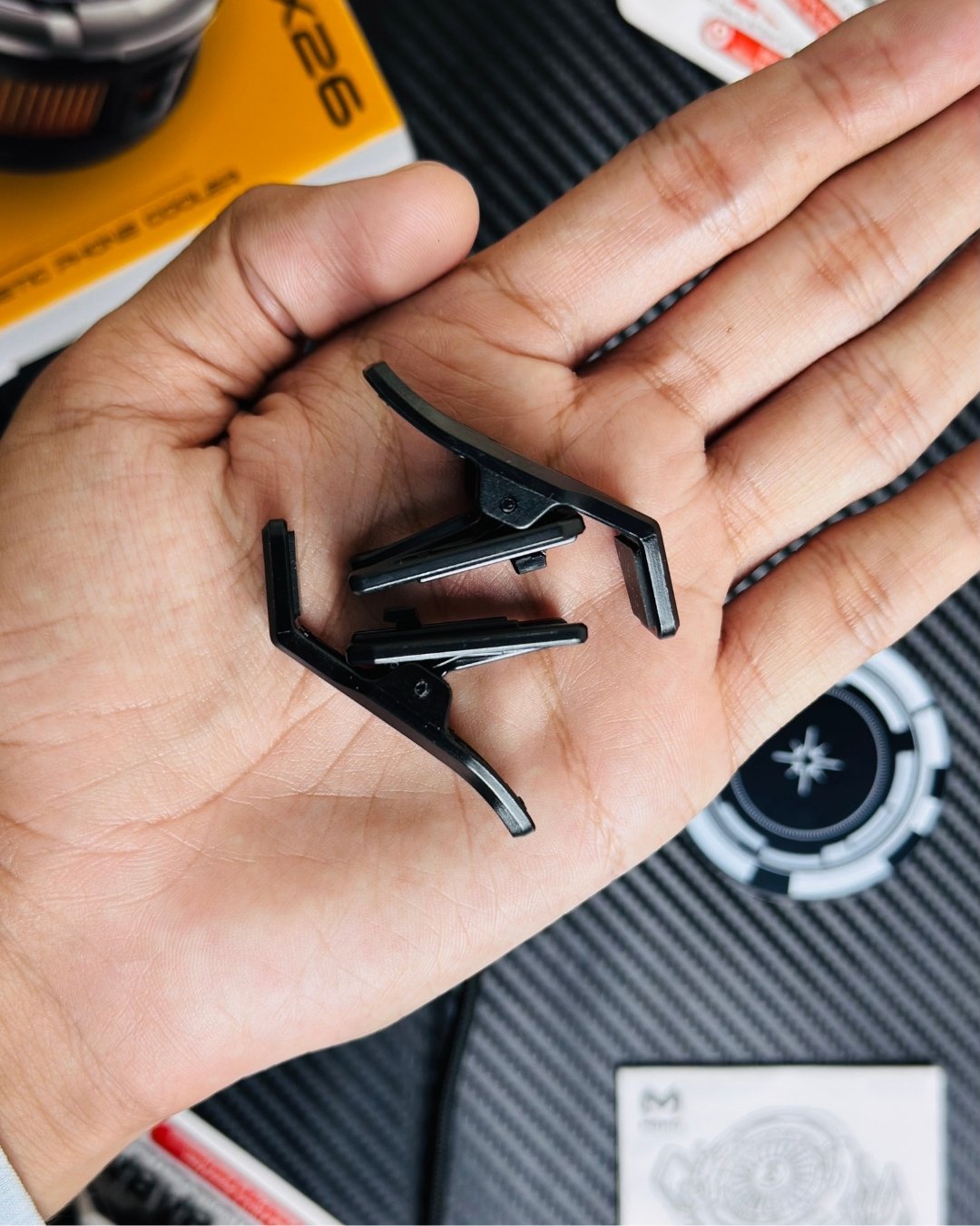a hand holding a clips that comes with MEMO_CX26_Ultra_30W_Phone_Cooler. picture by techbabastore.pk