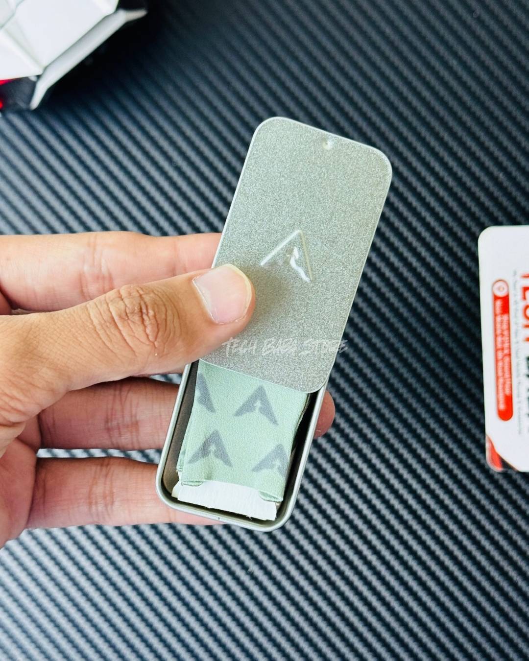 A hand holding half opened Piva DragonScale 2 thumb Sleeves Metalic box that comes with the thumbs. Picture by TechBabaStore.pk