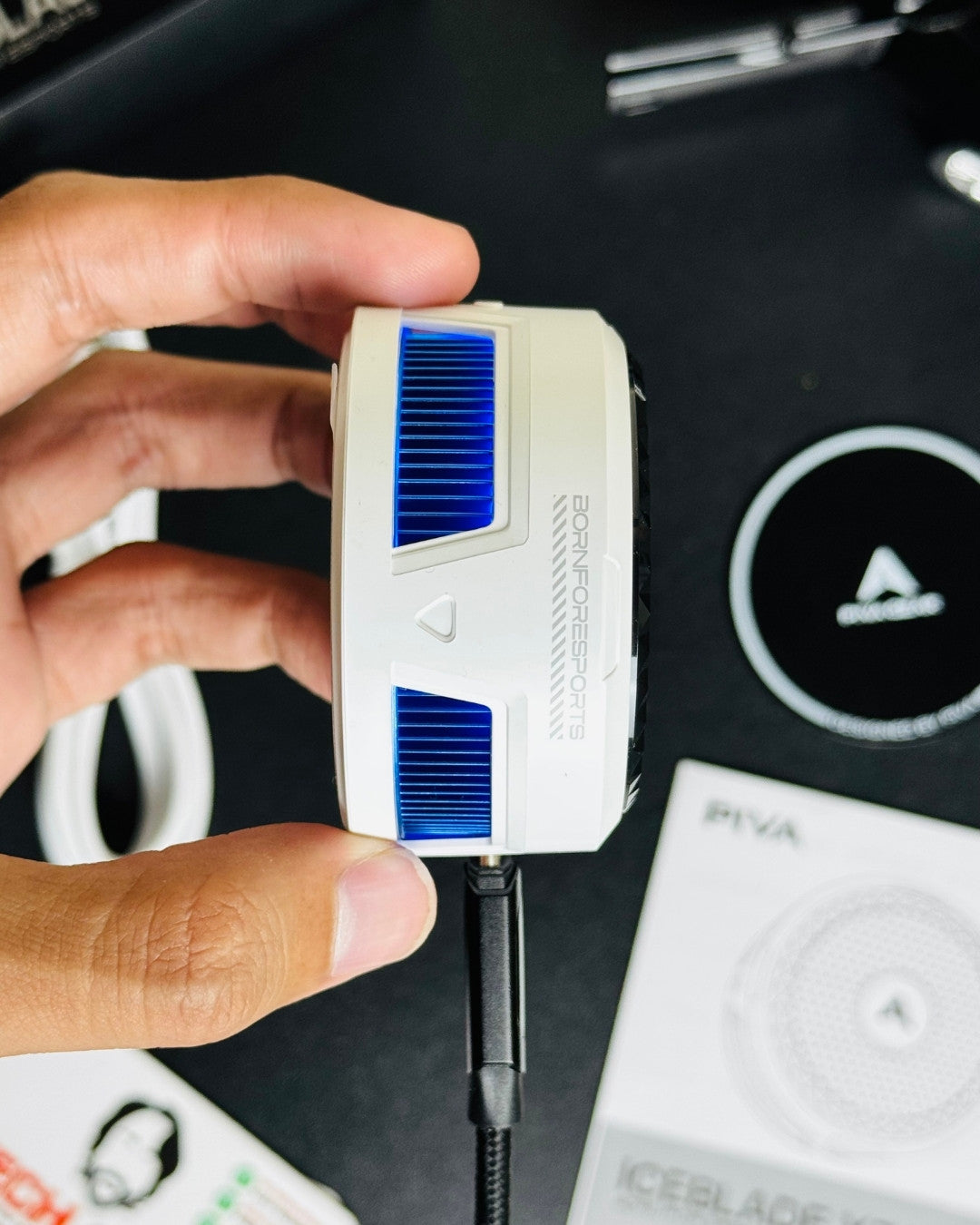 a hand holding a Piva X30 Mobile Cooling Fanand showing a side closup view and also showing a technical specification. picture by techbabastore.pk