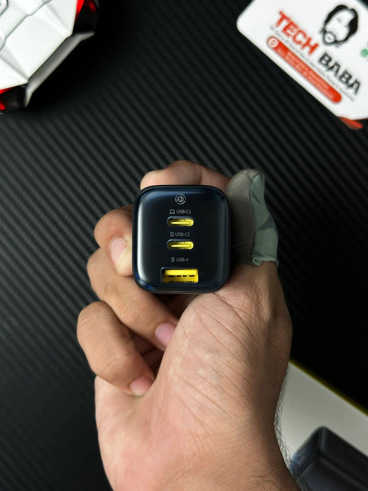 A hand holding Baseus_PicoGo_AE11_67W_GaN_Fast_Charger_2C_U_Dual_USB-C_USB-A_PD3.0_QC4.0_PPS which has showing All port.picture by TechBabaStore.pk 