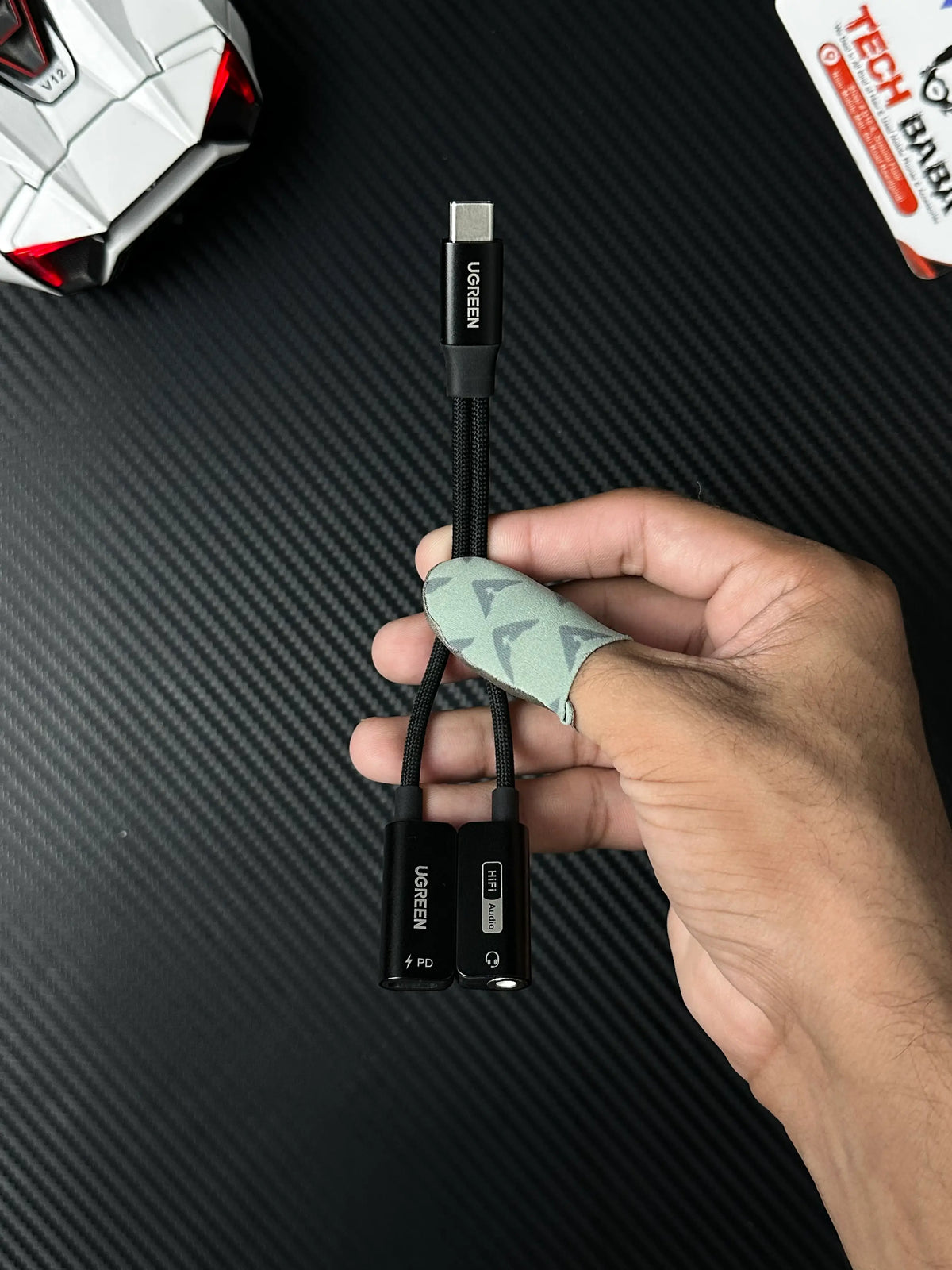 A hand holding UGREEN 25837 USB-C to 3.5mm Audio Adapter Pakistan which has showing cable .picture by TechBabaStore.pk