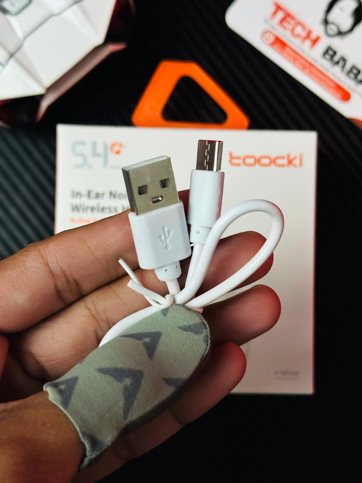 A hand holding Tocki Zero Delay Gaming Earbuds charging cable_picture by TechBabaStore.pk