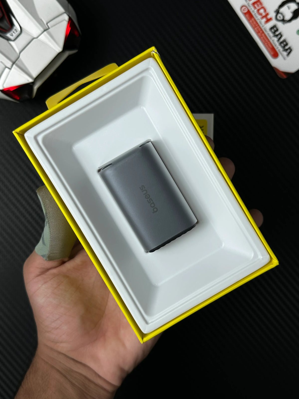 A hand holding baseus PicoGo AE11 67W GaN Fast Charger 2C+U — Dual USB-C + USB-A, PD3.0/QC4.0/PPS which has showing baseus  label  on  adpter.picture by TechBabaStore.pk