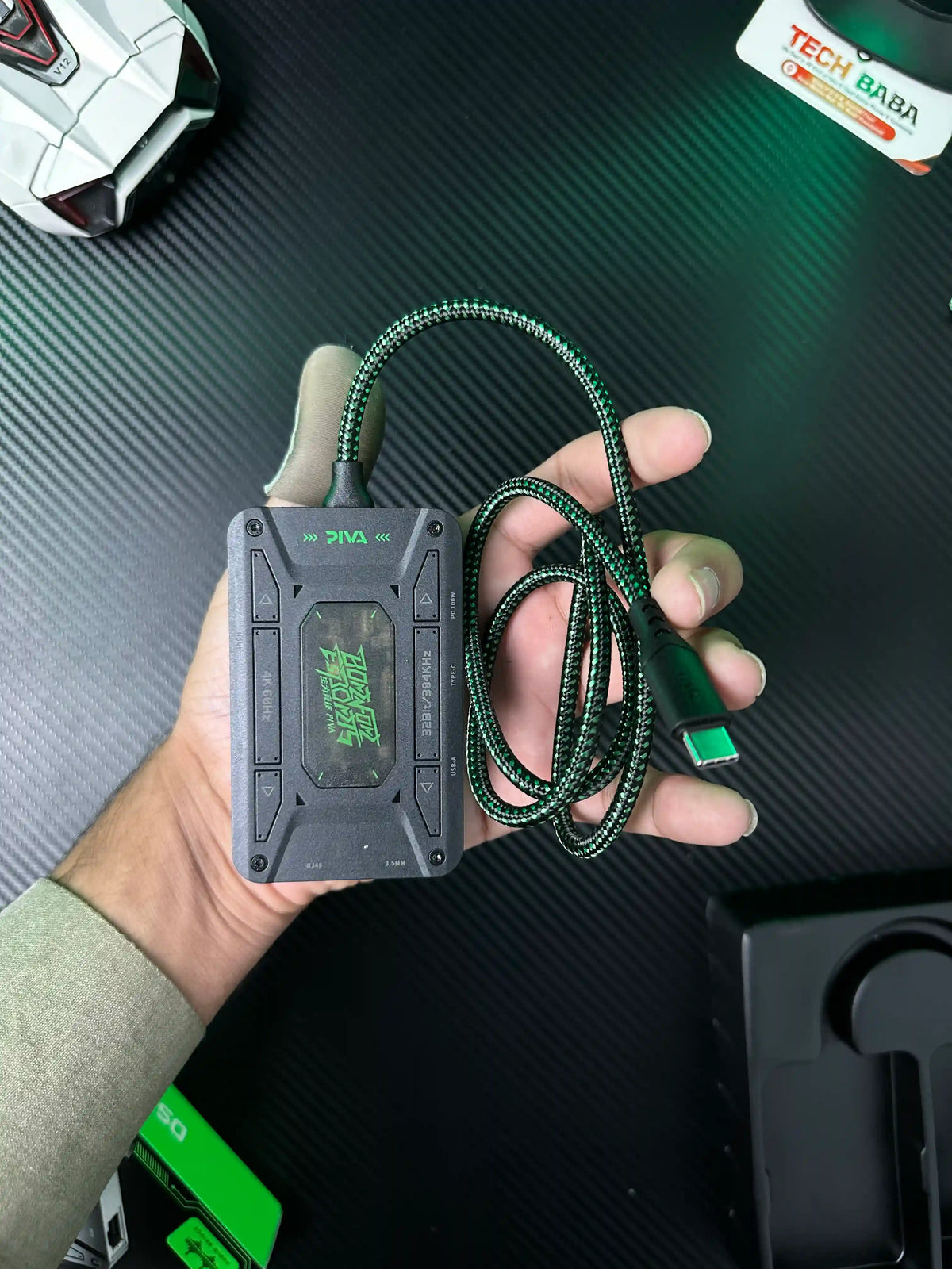A hand holding Piva DS7 7-in-1 Gaming Splitter — Ethernet, 100W PD, 4K HDMI for PUBG Mobile which has showing closeup shot of Piva DS7 7-in-1 Gaming Splitter — Ethernet, 100W PD, 4K HDMI for PUBG Mobile.picture by TechBabaStore.pk