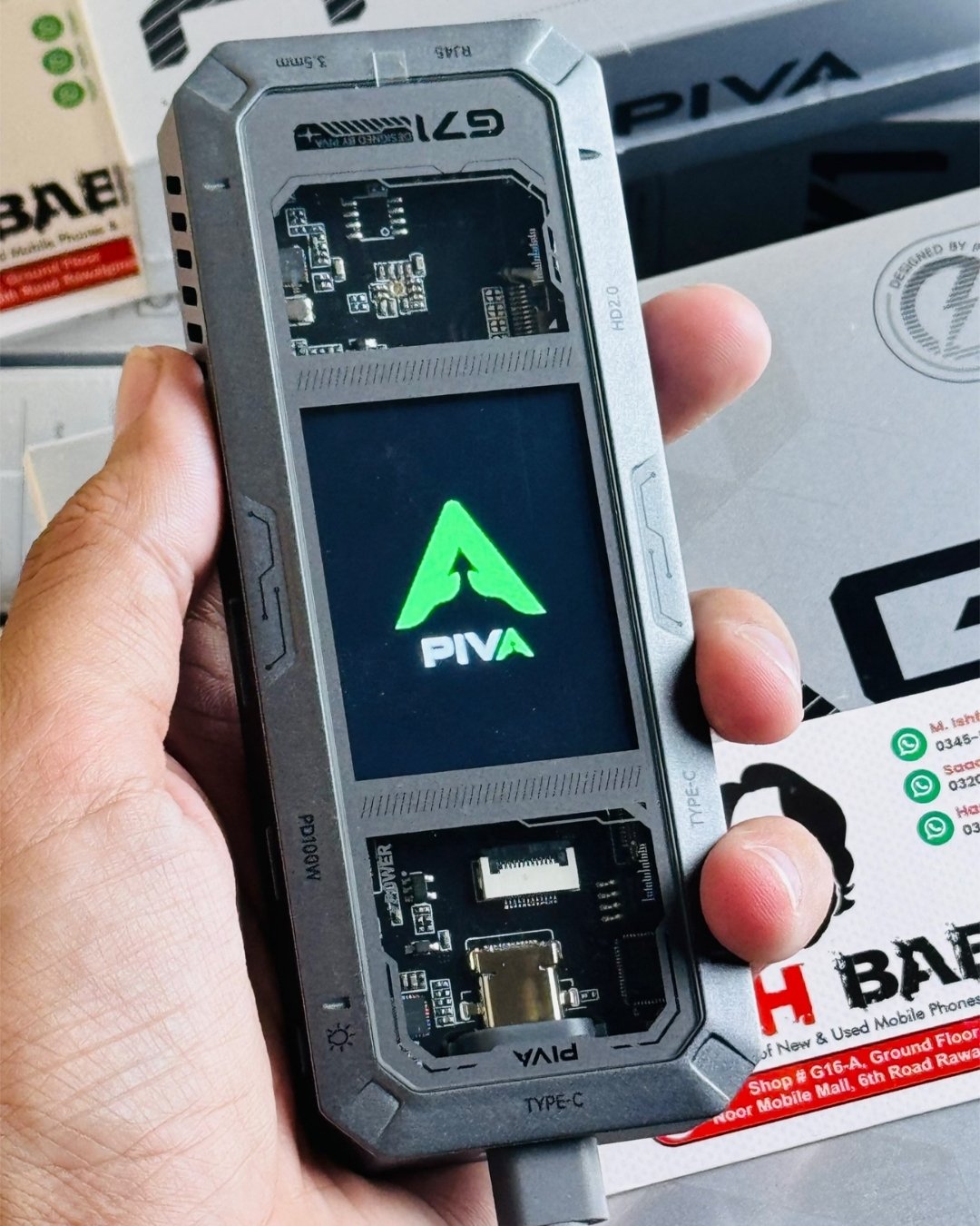A hand holding PIVA_G71_7-in-1_Gaming_Splitter_Docking_Station which has showing display-picture by TechBabaStore.pk