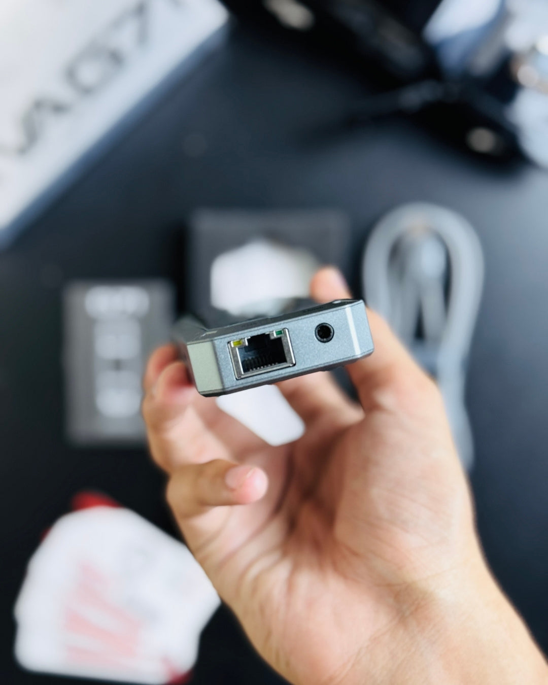 a hand holding PIVA_G71_7-in-1_Gaming_Splitter_Docking_Station which has ethernet +3.5mm_picture by Techbabastore.pk