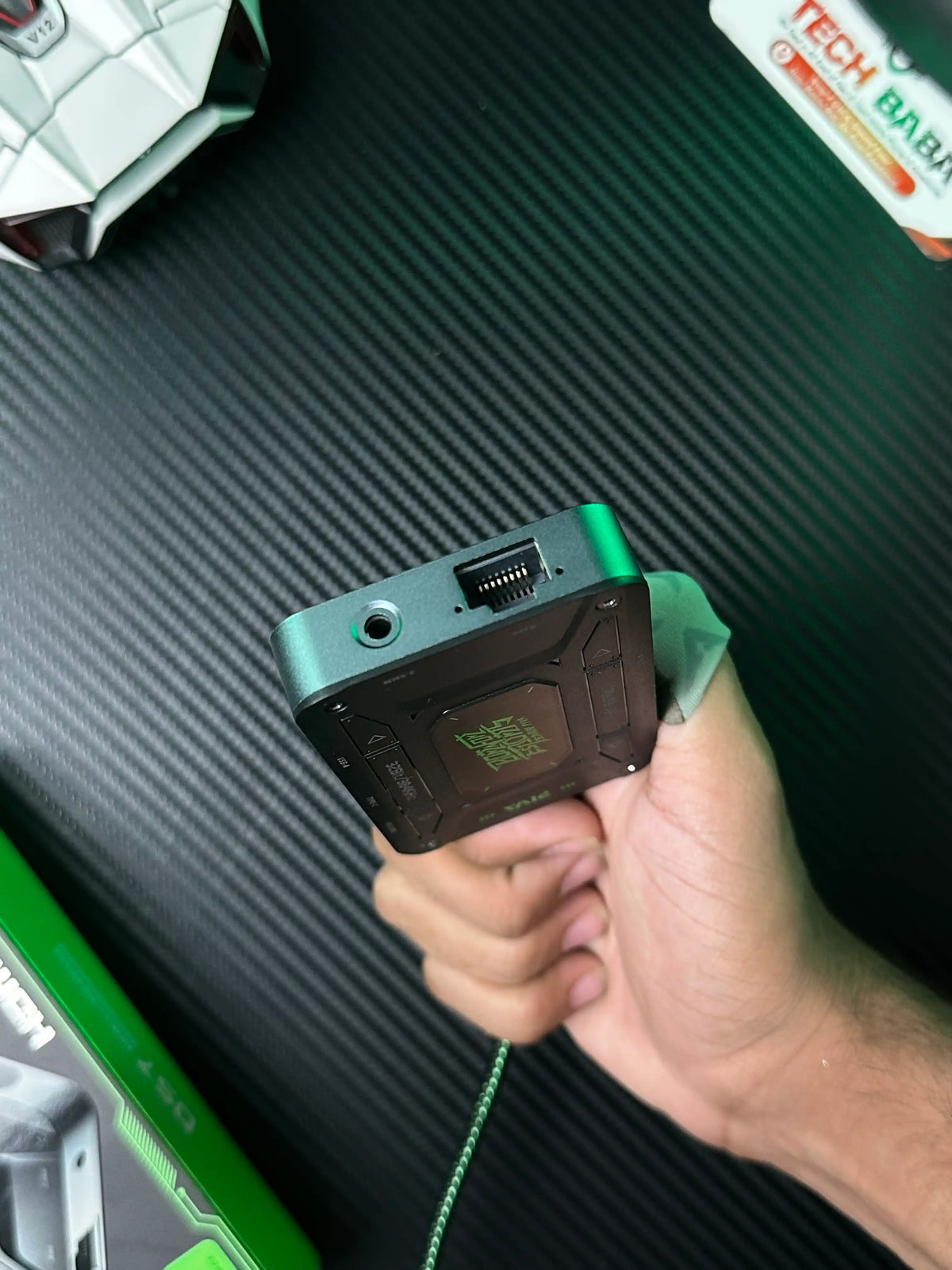 A hand holding Piva DS7 7-in-1 Gaming Splitter — Ethernet, 100W PD, 4K HDMI for PUBG Mobile which is showing an RJ45 ethernet connector and 3.5mm Headphones Jack of Piva DS7 7-in-1 Gaming Splitter — Ethernet, 100W PD, 4K HDMI for PUBG Mobile.picture by TechBAbaStore.pk