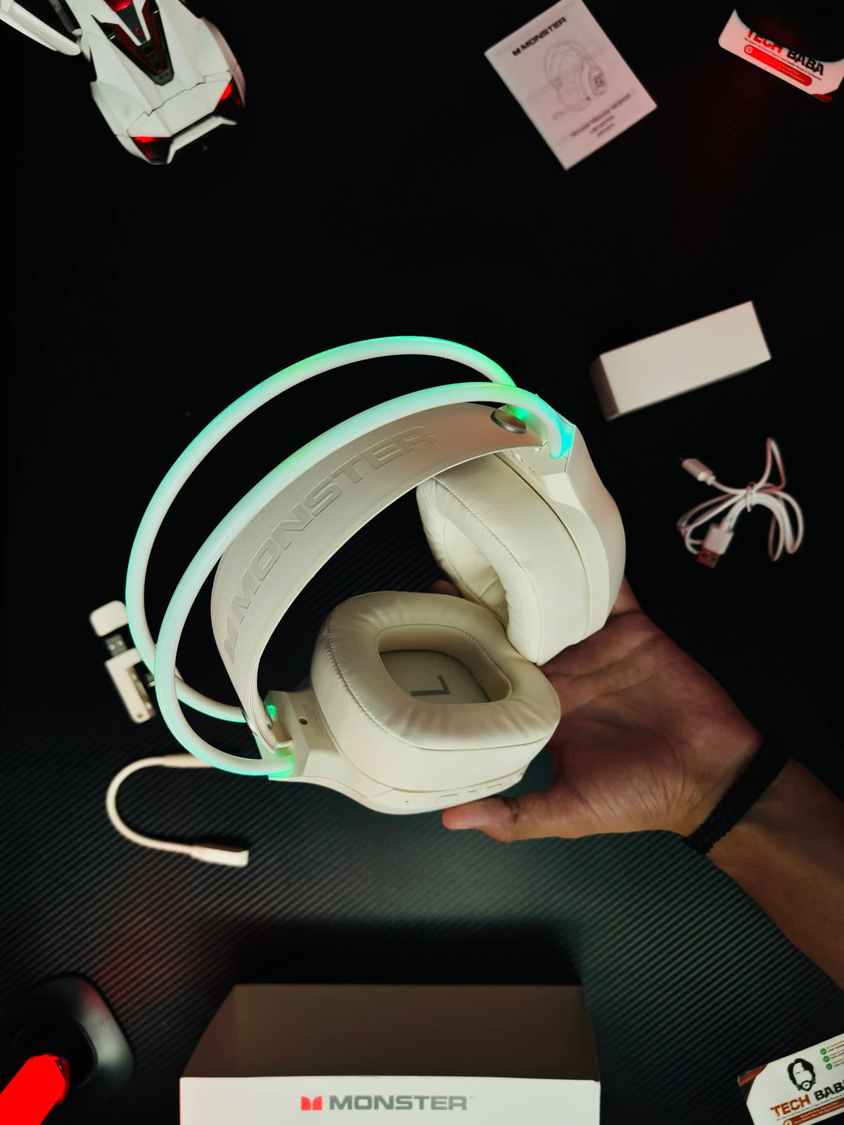 A hand holding Monster_Maxstar_MQH09_Wireless_Gaming_Headphone_50mm_Driver_Bluetooth_5.4_IPX5_Best_PUBG_Headset_Pakistan_which has showing label of monster.picture by TechBabaStore.pk
