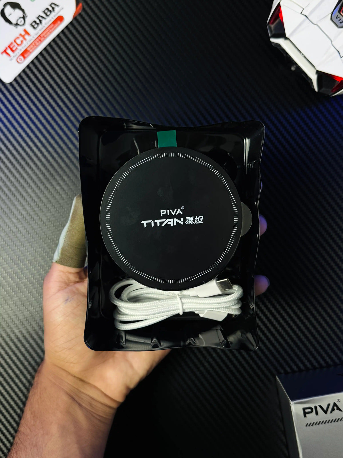 A hand holding Piva Titan T300 iPad Cooler — 45W Semiconductor Cooling Fan for PUBG Mobile which has showing magnetic plate and wired.picture by TechBabaStore.pk