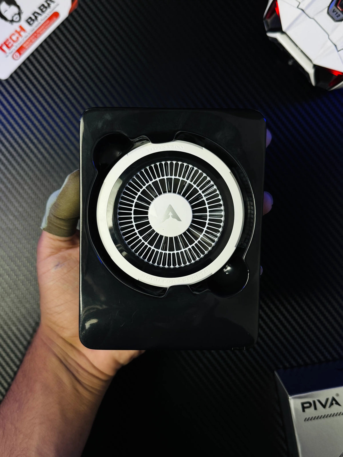 A hand holding open box of Piva Titan T300 iPad Cooler — 45W Semiconductor Cooling Fan for PUBG Mobile which has sgowing colling fan with label of piva .
picture by TechBabaStore.pk