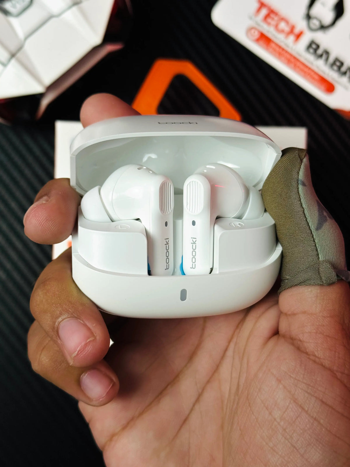 A hand holding Tocki Zero Delay Gaming Earbuds open charging cas_ picture by TechBabaStore.pk