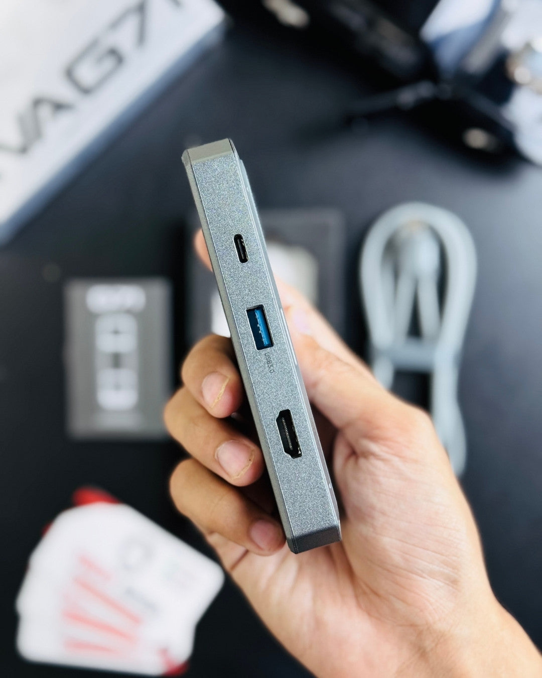 A hand holding PIVA_G71_7-in-1_Gaming_Splitter_Docking_Station which has showing ports picture by Techbabastore.pk