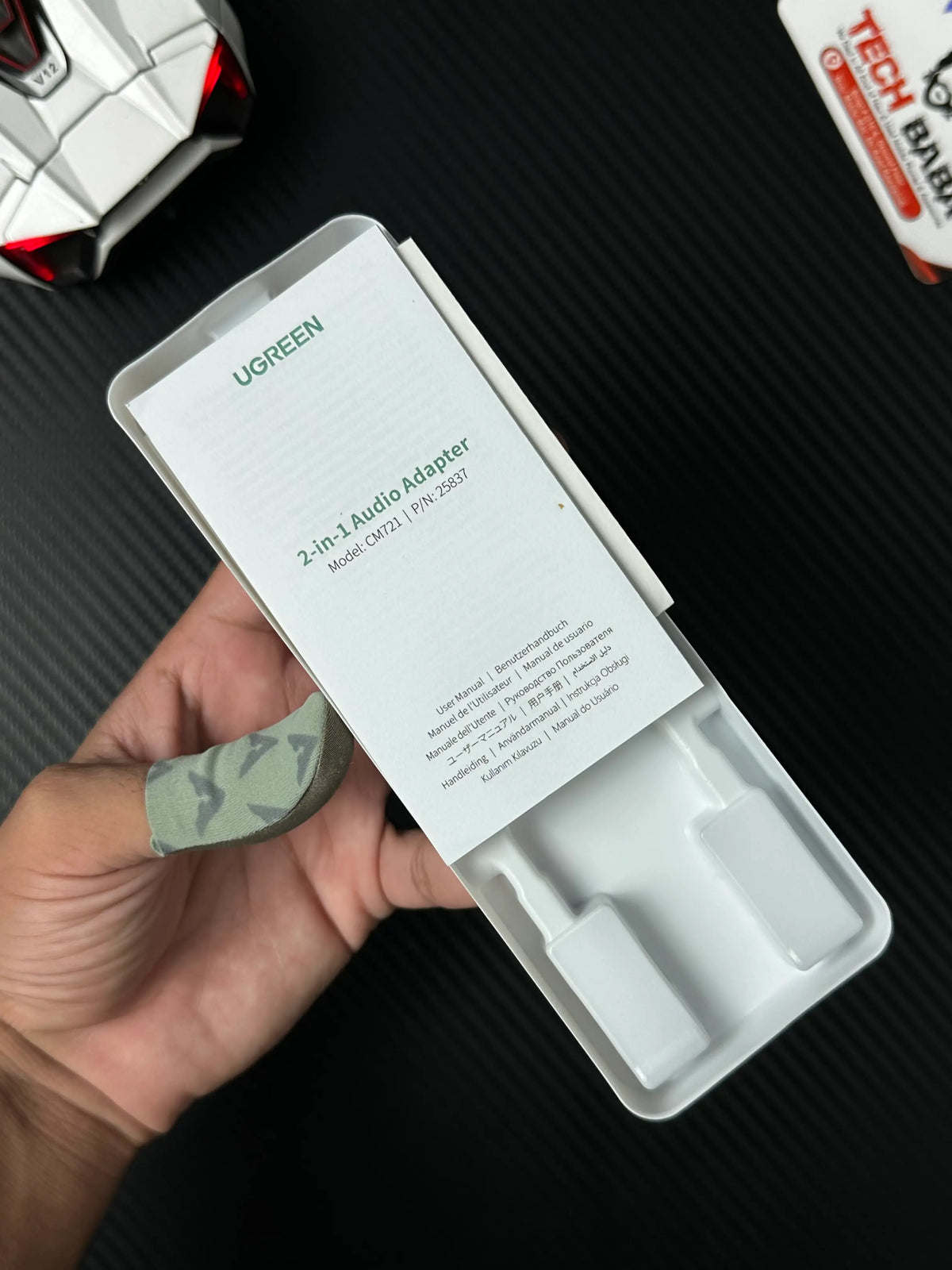 A hand holding UGREEN 25837 USB-C to 3.5mm Audio Adapter Pakistan which has showing specification in box picture by TechBabaStore.pk