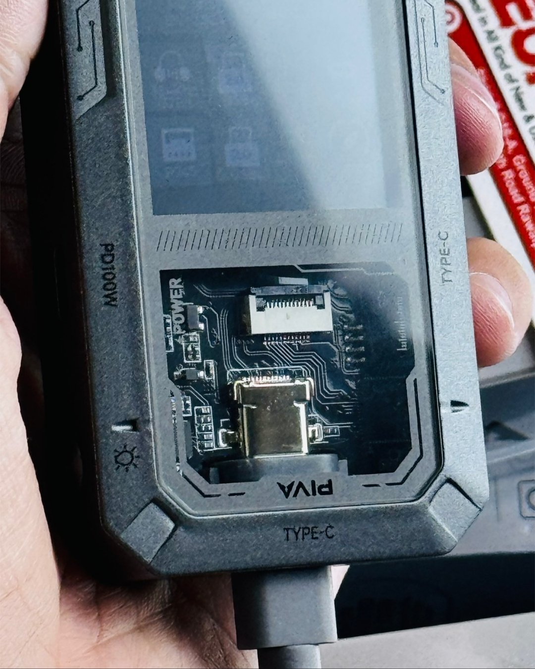 a hand holding PIVA_G71_7-in-1_Gaming_Splitter_Docking_Station which has showing transparent view_picture by TechBabaStore.pk