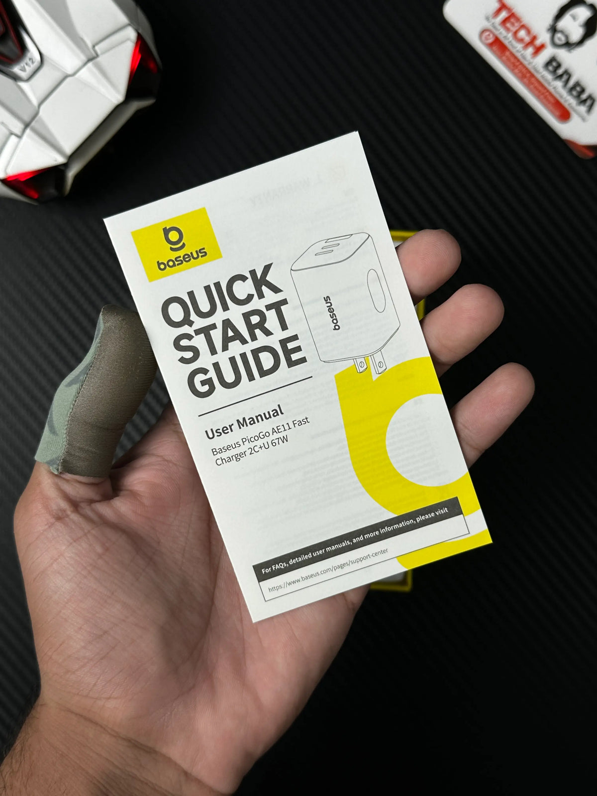 A hand holding user manual of  Baseus PicoGo AE11 67W GaN Fast Charger 2C+U — Dual USB-C + USB-A, PD3.0/QC4.0/PPS.picture by TechBabaStore.pk